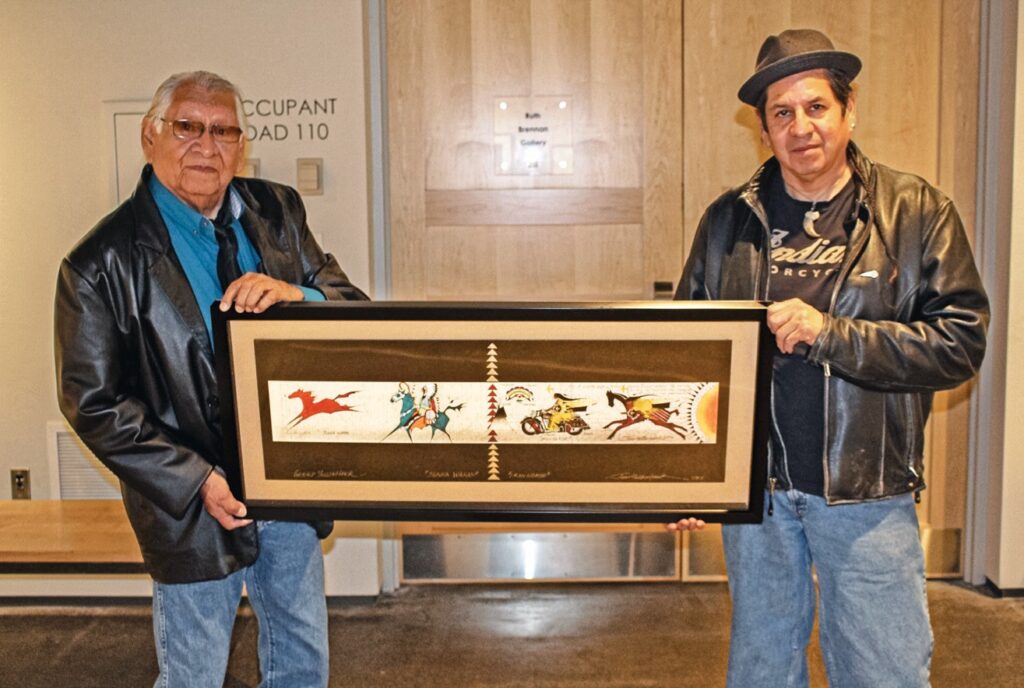 Rev. Dr. Gerald Yellowhawk and his son Jim Yellowhawk hold an art piece they’ve done together for the Ate Chinhintku Kici Wakpazopi exhibit at the Dahl Arts Center in Rapid City beginning on December 1, 2017. (Photo by Richie Richards)
