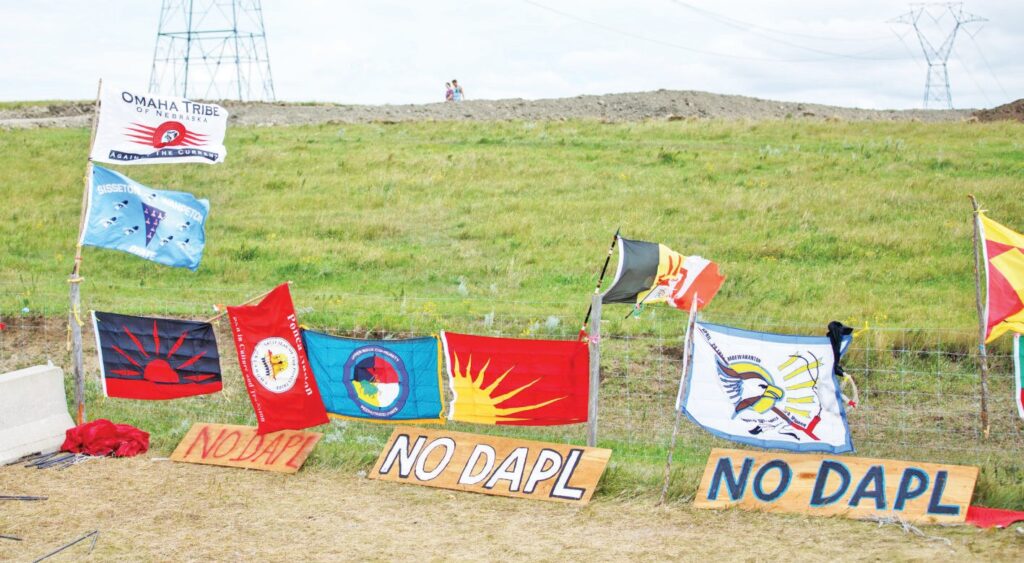 Tribal flags hang on a fence in August 2016 near the construction site of the Dakota Access Pipeline north of Cannon Ball, N.D. (Photo by Kyle Martin/For the North Dakota Monitor)