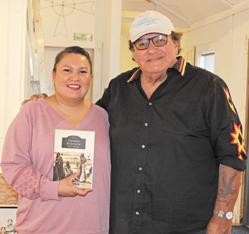 Chantelle Blue Arm stands with her uncle, historian Donovin Sprague, at Racing Magpie on June 15 as he signs her copy of Images of America: Cheyenne River Sioux Tribe. (Photo by Ernestine Anunkasan Hopa)